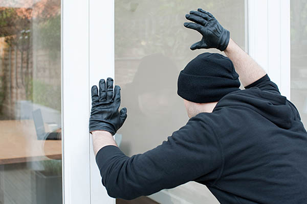 A bad guy trying to break into a home with safety window film.