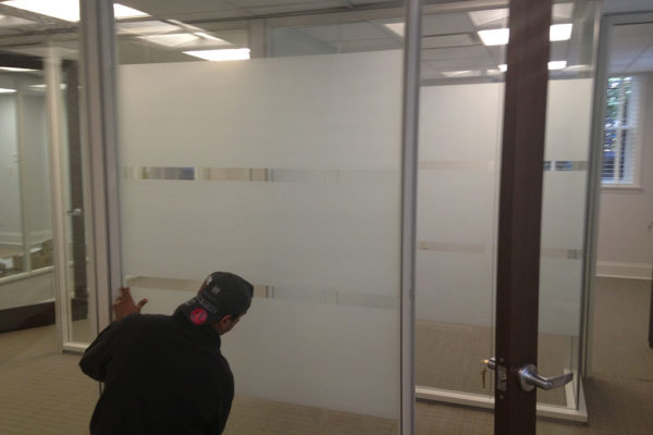 Technician installing 3M decorative window film.